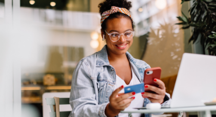 Woman holding credit card sitting at her laptop