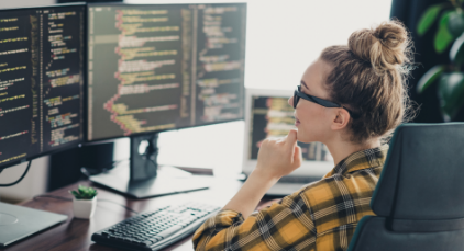 woman looking at dual computer screens
